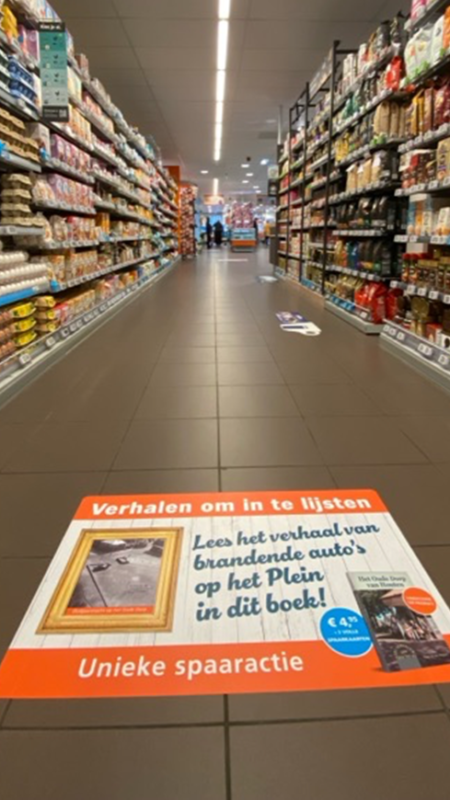 Vloersticker in een supermarktgang die reclame maakt voor een actie.